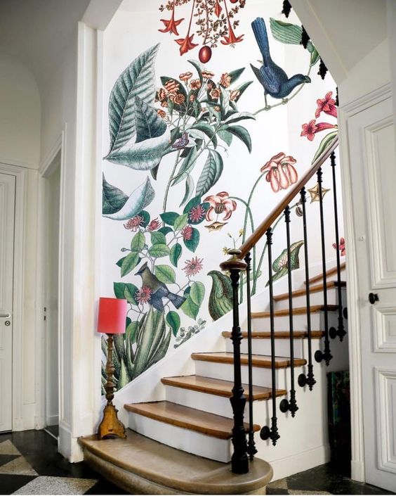 a refined entryway with a classic staircase and fantastic bright floral and faune wallpaper plus a little floor lamp in red