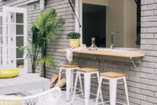 18 an outdoor-indoor bar with stools, a countertop and a dining space by its side plus some potted greenery