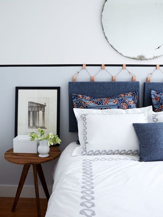 a hanging headboard made of blue denim on amber leather holders and a matchign denim pillow on the bed