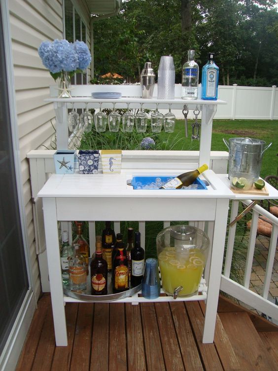 a stylish and simple outdoor bar station with glasses, bottles and even a wine cooler