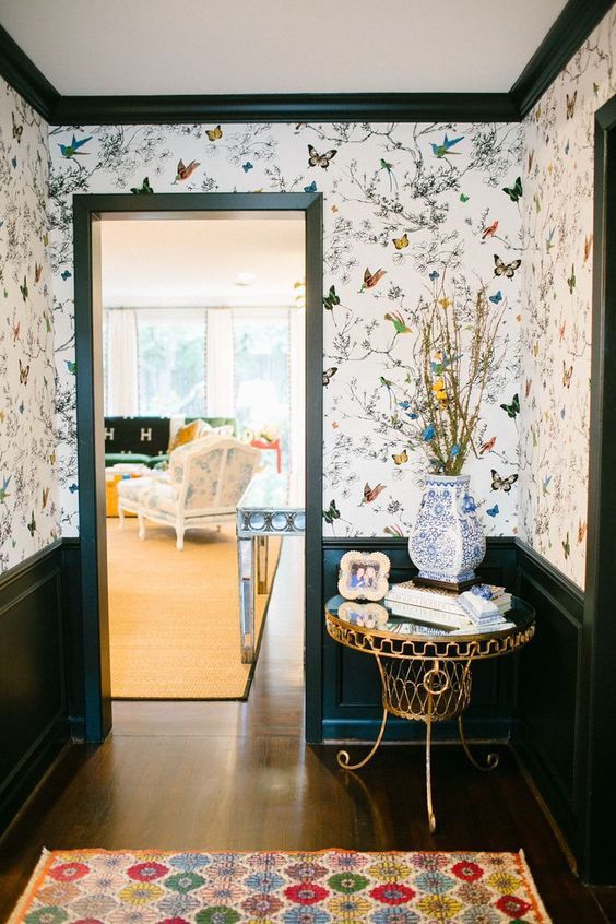 a whimsy entryway with bright flora and fauna wallpaper and chic and refined furniture plus a rug