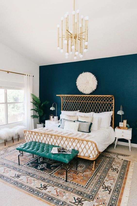 a chic bedroom spruced up with a potted plant, a gold chandelier and an arrangement of throws