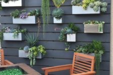 23 a black wooden plank wall with concrete and metal planters attached and lots of succulents and cacti