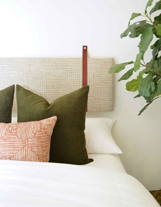 a neutral yet printed headboard of a long cushion on leather straps looks cool and bold
