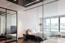 24 a contemporary bedroom with a large dark metal sunken bathtub separated with glass to avoid splashes on the floor