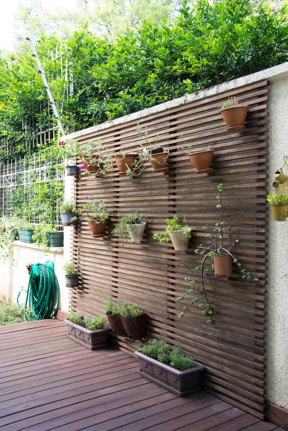 a dark wooden plank wall with various planters attached is a simple idea to enliven your space
