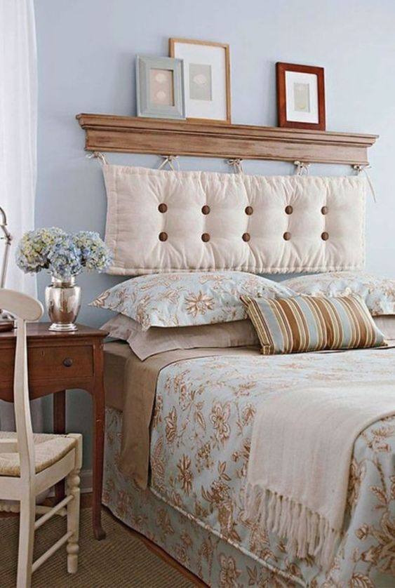 A vintage inspired bedroom in pastel blues, tan and creamy, with a cushion headboard hanging on a small shelf