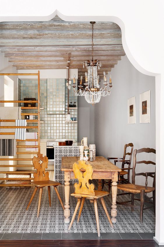 an eclectic space with printed tiles, a wooden dining set and a gorgeous crystal vintage chandelier over the space