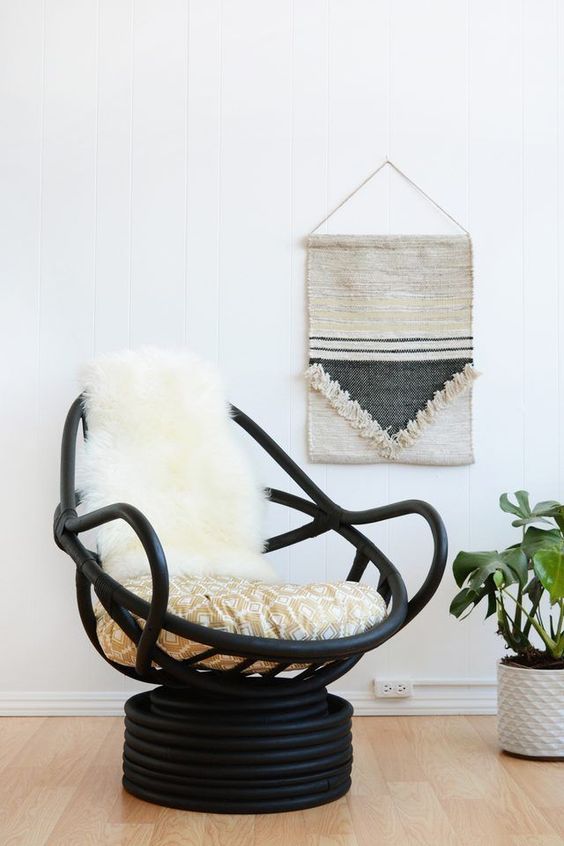 a modern black wooden papasan swivel rocker with neutral upholstery and faux fur