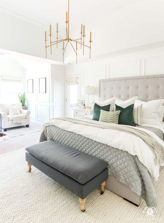 a neutral bedroom with a grey statement bed, an arrangement of pillows