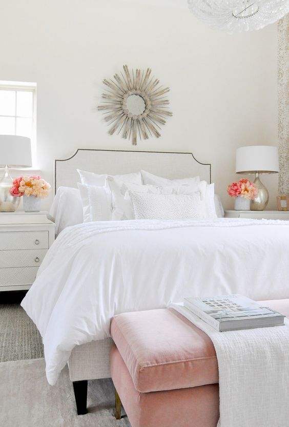 a chic and airy bedroom with a white bed and an arrangement of white pillows but of various fabrics