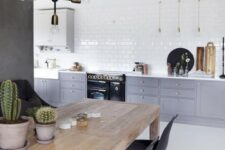 a Scandinavian kitchen with grey and white cabinets, white subway tiles, a wooden table and black chairs is very fresh