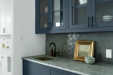 a lovely blue kitchen with a gray backsplash
