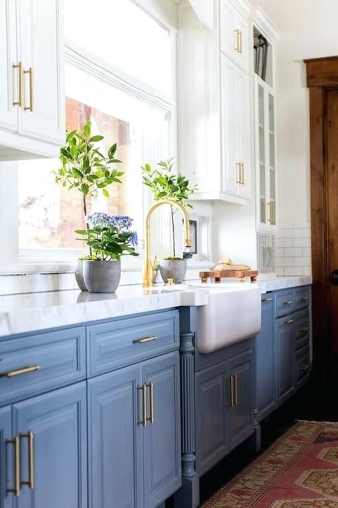 a beautiful kitchen with light blue lower cabinets, white upper ones, gold touches and potted blooms