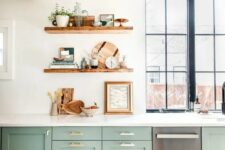 a beautiful sage green kitchen with white stone countertops, open shelves, rich stained touches and gold handles is very chic