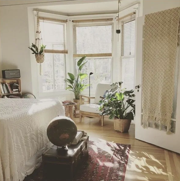 a biophilic boho bedroom with potted plants, lots of natural light and natural textiles plus rugs
