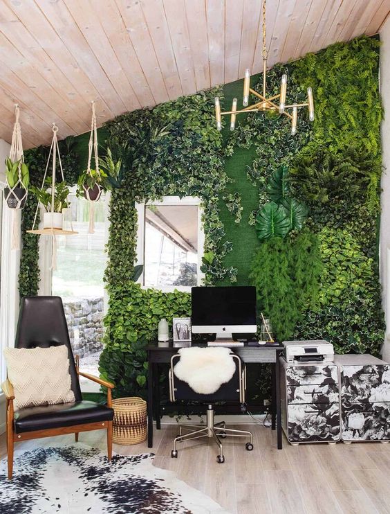 a biophilic home office with a greenery wall and potted plants hanging from above looks very fresh