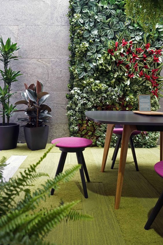 a biophilic space with a greenery wall, a rug that imitates moss and grass, potted plants for a fresh feel