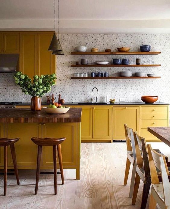 a bold kitchen with mustard cabinets, wooden countertops, a white tile backsplash and touches of wood here and there