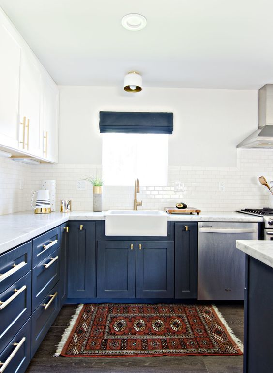 a bold kitchen with navy lower cabinets, white upper ones, gold touches, a bold boho rug and navy shades