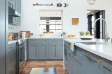 a bright kitchen with grey cabinets, white walls and countertops and touches of gold here and there