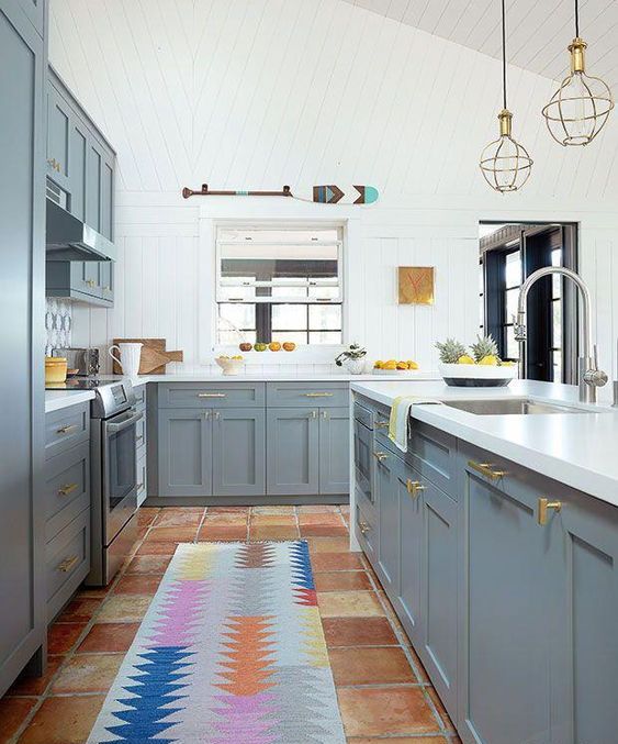 a bright kitchen with grey cabinets, white walls and countertops and touches of gold here and there