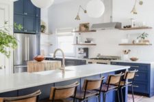 a bright modern kitchen with bold blue lower cabinets and a kitchen island, white countertops and a backsplash