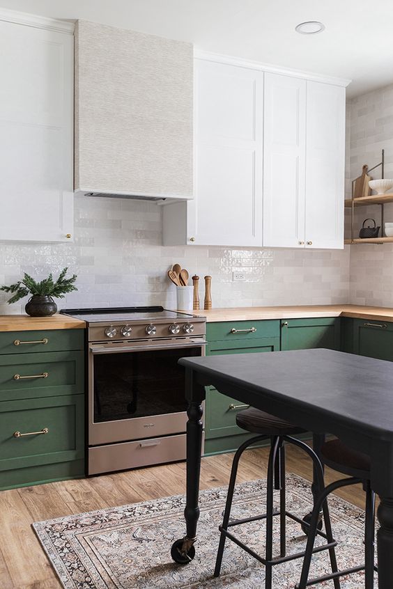 a chic and bold kitchen with white and green cabinets, metallic touches, wooden countertops and a dark grey kitchen island
