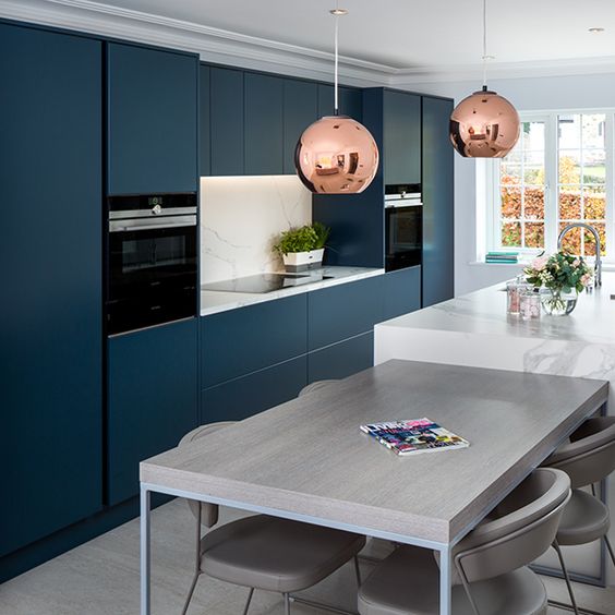 a chic contemporary navy kitchen with a white kitchen island and matching countertops plus a grey table for breakfasts