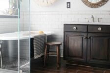 a chic contrasting bathroom with a dark wood tile floor, white subway tiles on the walls, a dark vanity, a shower and a tub