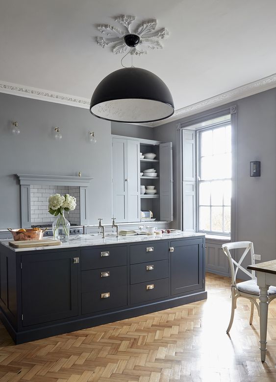 a chic dove grey kitchen with a midnight blue kitchen island and touches of brass that make it more refined and gorgeous