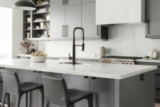 a chic modern monochromatic kitchen with grey cabinets and a kitchen island, white marble countertops and a backsplash, black pendant lamps and black stools