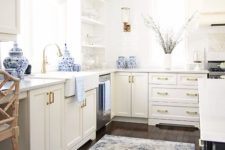a chic neutral kitchen spruced up with a blue rug and some porcelain and touches of gold for more chic
