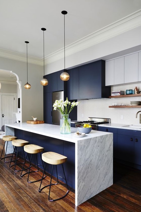 a chic two tone kitchen in white and navy, with a white marble countertop and tile backsplash plus wooden stools