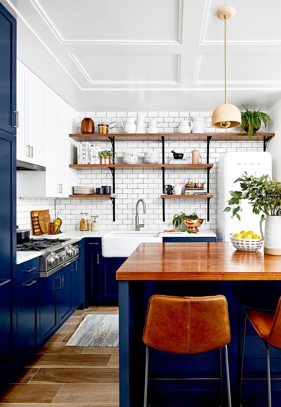 a classic blue kitchen with a white subway tile backsplash, white countertops and wooden open shelves