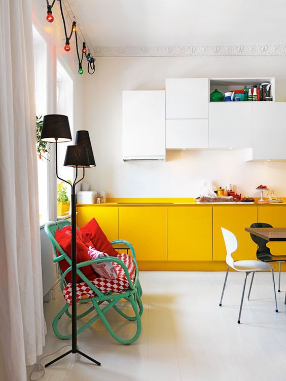 A contemporary kitchen with white and yellow cabinets and built in lights plus colorful touches for more