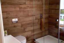 a contemporary rustic bathroom all clad with wood look tiles – the walls and the floor for a warm feel