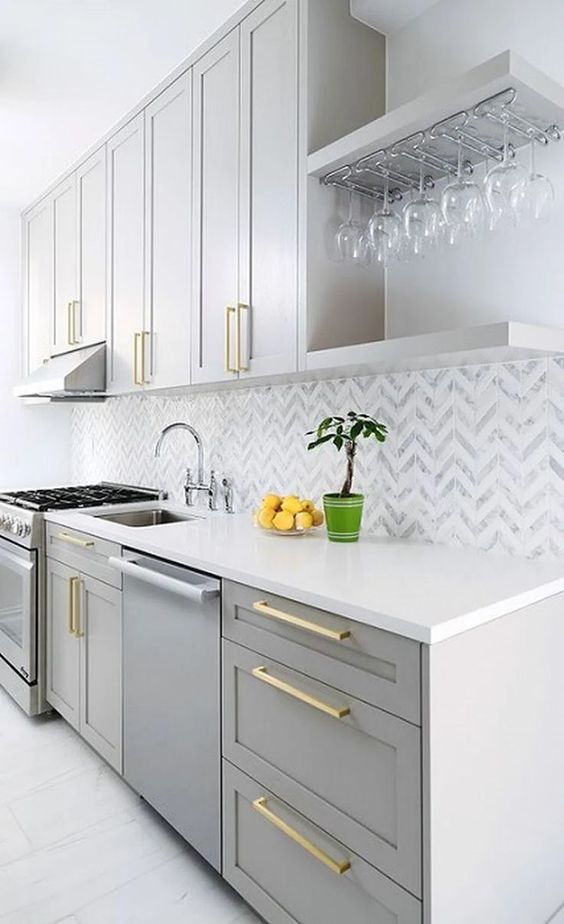 a contemporary with dove grey cabinets, a chevron tile backsplash and gold handles looks very chic and elegant