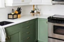 a cool two-tone kitchen with white and olive green shaker cabinets, white stone countertops and a white subway tile backsplash and gold knobs