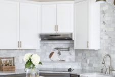 a farmhouse kitchen with upper white cabinets, graphite grey ones, a marble tile backsplash and a stained kitchen island