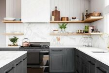 a gorgeous contrasting kitchen with graphite grey cabinets, white countertops and a backsplash, a hood, wooden shelves for a softer look