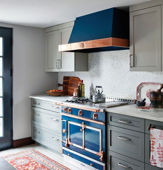 a grey art deco kitchen with a bright blue cooker and copper touches plus a mosaic tile backsplash looks wow