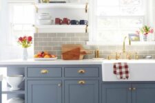 a lovely and cozy kitchen with blue shaker style cabinets, a grey subway tile backsplash, a bold blue tiled floor and open shelves