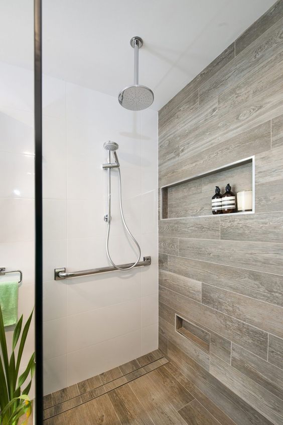 A lovely bathroom with wood tiles and a niche and a matching floor in the shower space to add an eye catching touch