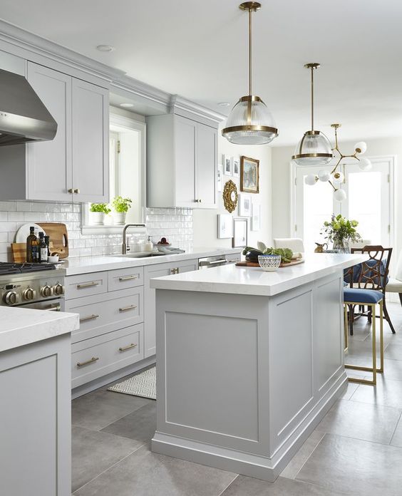 a mid-century modern kitchen with dove grey cabinets, gold touches and chic lamps and chandeliers for a stylish feel
