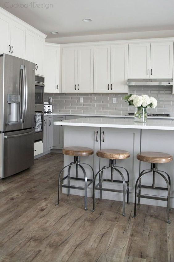 A mid century modern kitchen with dove grey lower cabinets, white upper ones, a grey tile backsplash and a grey kitchen island