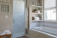a mid-century modern tan bathroom with tan walls, wood look tiles on the floor, built-in shelves and white subway tiles