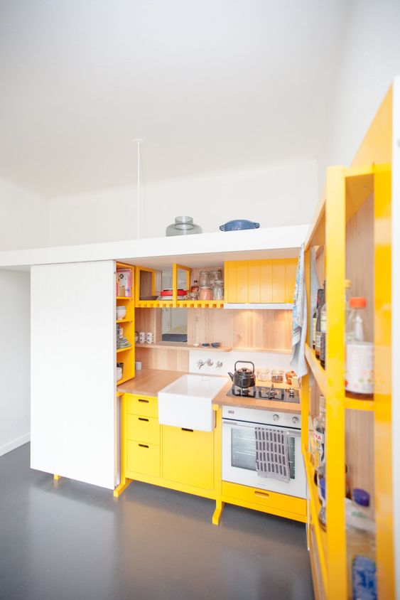 a mini contemporary kitchen done in sunny yellow and with natural wood touches plus built-ins is bold