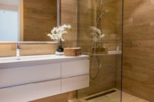 a minimalist bathroom fully clad with wood look tiles on the walls and floor plus a white floating vanity