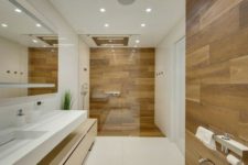 a minimalist bathroom with white large scale tiles and wood look tiles in the shower space and an accent by the toilet